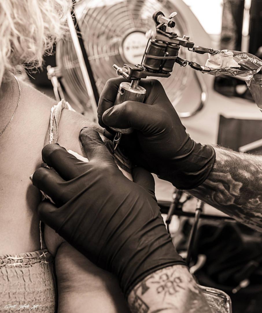 Tatoueur faisant un tatouage sur une femme au bras